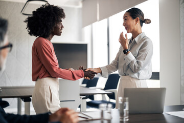 Diverse businesswomen shaking hands during office meeting
