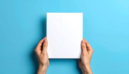 Hands holding blank white paper against a blue background.