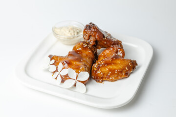 Close-up of chicken wings in teriyaki sauce with sesame seeds and floral garnish