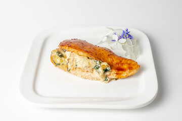 Close-up of stuffed chicken breast with cheese and spinach on white plate