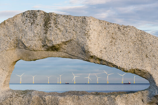 The stones known as Windows To The Sea overlook the wind turbines in the North Sea near Aberdeen, Scotland, UK