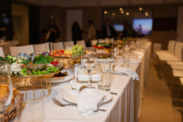 Wide shot of long set table with buffet and wine glasses at event