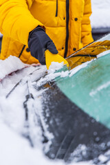 Removing snow and ice from car windshield.