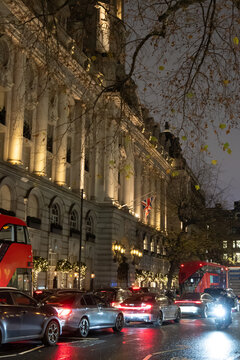 London streets at night glow with car headlights and reflections on wet roads, creating lively, atmospheric cityscape