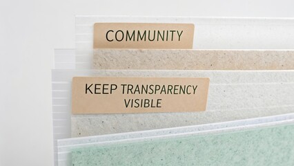 Organized file folders with labels emphasizing community, transparency, and visibility in a professional office setting