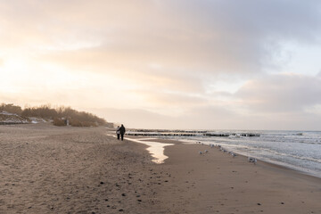 a loving couple walks along the coast in winter
