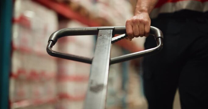 Logistics, loader and hands with pallet truck, warehouse and restock for goods distribution or pull. Moving, cargo and person with equipment for supply chain in factory, merchandise and shipping