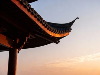 Traditional East Asian temple roof at sunset with curved eaves and tiled details