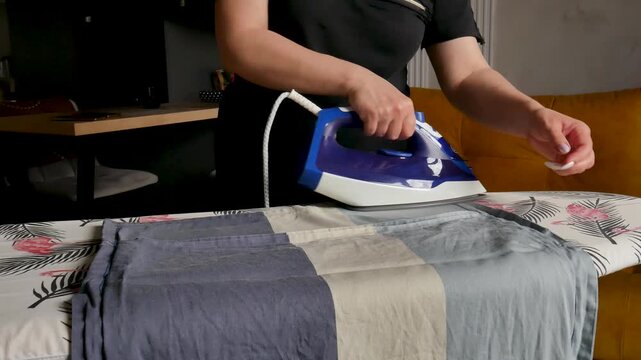 Woman ironing clothes on ironing board, housework