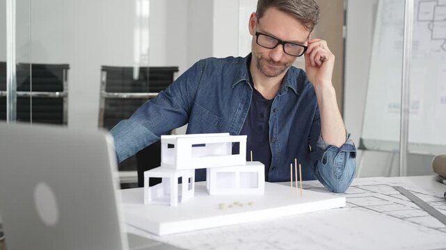 Stressed architect feeling overwhelmed and frustrated, suffering from burnout while working on blueprints for a tight project deadline in a modern office setup