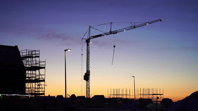 A crane at a construction site during a colourful, winter sunrise. Meerstad, the Netherlands
