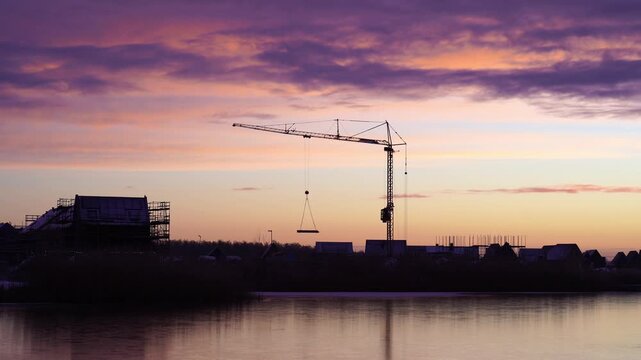 A crane at a construction site during a colourful, winter sunrise. Meerstad, the Netherlands