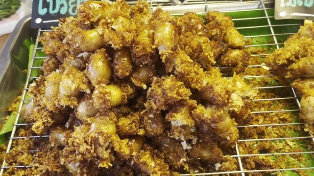 Grilled Thai Isan sausages and meatballs on skewers, a popular traditional street food in Thailand. Close-up shot of savory sausages and meatballs being grilled over charcoal, with smoke rising and ap