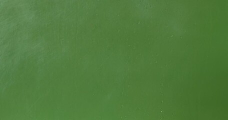 Close up of sprayed liquid and wet glass with water droplets and rain streaks on a bright green chroma key background, ideal for visual effects and background replacement. Slow motion. - Powered by Adobe