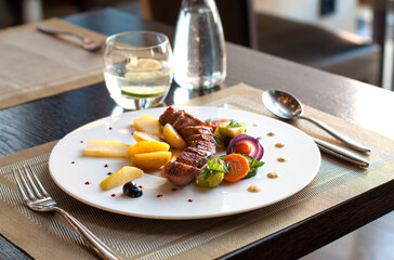 Plate with grilled meat (pork loin) and vegetables in restaurant