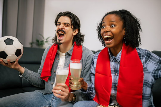 Multiracial Couple Watching Football with Snacks - Powered by Adobe