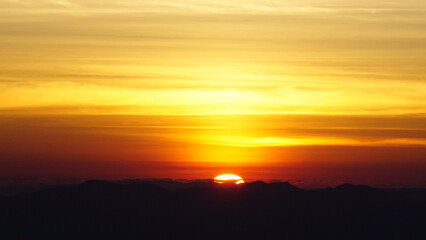 Golden sunrise touching the horizon over mountain silhouettes