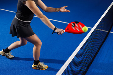 Indoor padel net volley by female player on blue court