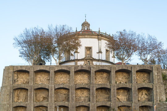 View of Mosteiro Santo Agostinho da Serra do Pilar chapel rises above a multi-layered stone structure under a pale sky, framed by bare trees in Porto, Porto District, Portugal.