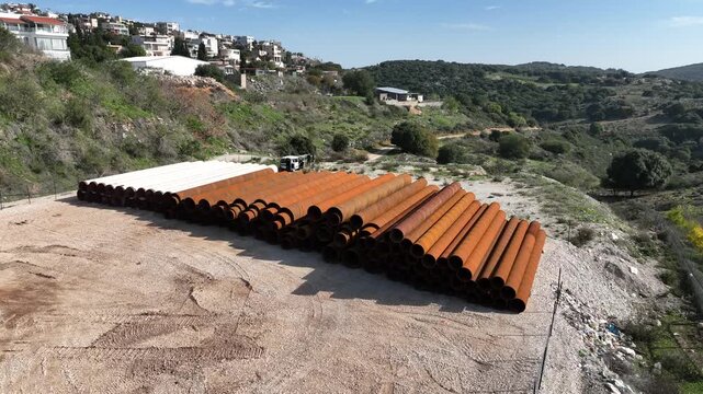 Northern Israel, Israel - January 15 2025: Aerial view of stacked heavy industrial steel pipes
Cinematic drone footage showing a large pile of heavy industrial steel pipes stacked outdoors in an indus