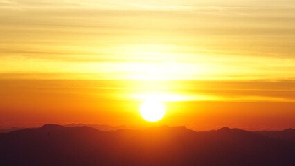 Glowing sunrise over distant mountain silhouettes