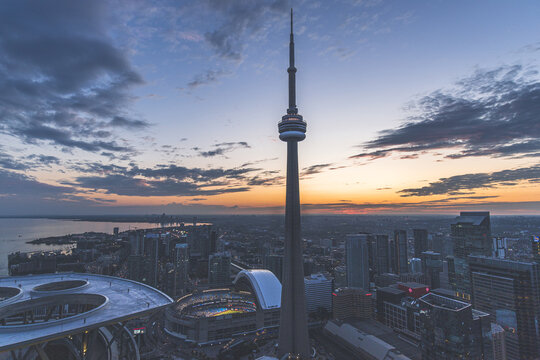 View of the CN Tower piercing the twilight sky as the city lights begin to twinkle, a vibrant urban panorama unfolds below, Toronto, Ontario, Canada.