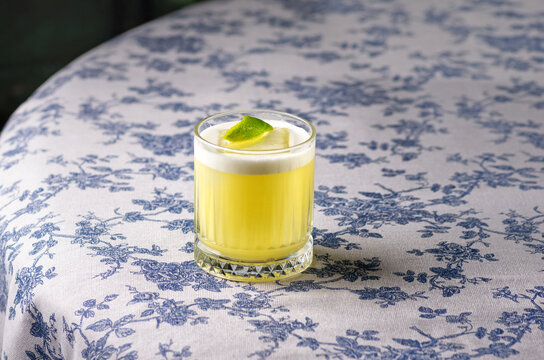 Pisco sour cocktail - whiskey with lime, egg white, sugar syrup in glass on dark background. Space for text