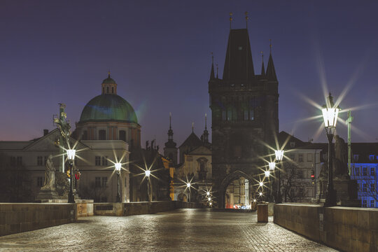 View of the cobblestone bridge stretching towards the gothic tower and baroque dome under the fading twilight, Prague, Prague, Czechia.