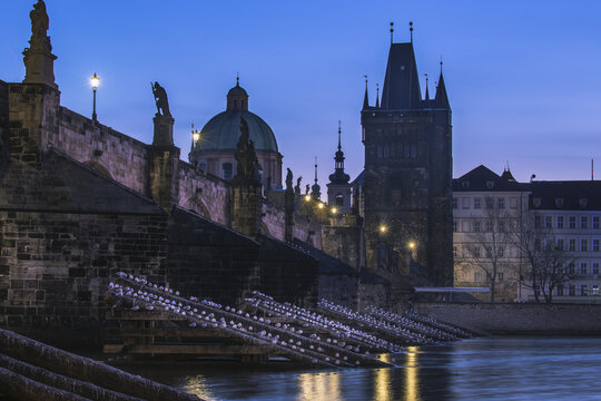 View of the dark silhouette of Charles Bridge rises against the deepening blue of twilight, with statues standing guard over the Vltava River, Prague, Prague, Czechia.