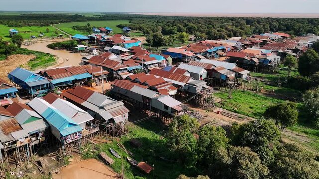 Aerial view of kampong phluk, a traditional floating village with stilt houses on the tonle sap lake in cambodia during a golden sunset.