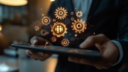 Hands hold tablet displaying glowing golden gears, a networked system, and a people icon