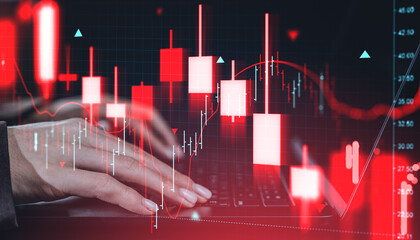 Trading chart with red candlesticks and hands on laptop symbolizing financial market crash and investment crisis concept in a digital environment.