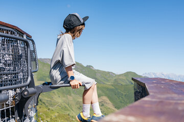 Young boy wearing cap enjoying mountain view from observation deck