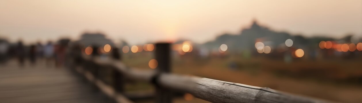 A scenic view of U Bein Bridge at sunset, framed by a railing, blurred tourist background