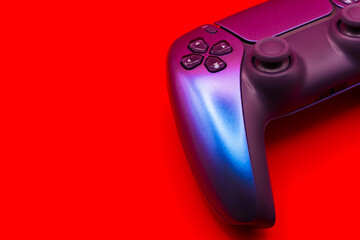 A gamepad for consoles on a red background, gaming addiction, gaming ban for teenagers, gaming controls for parents, for banners and advertising. High quality © Karen Vardanian