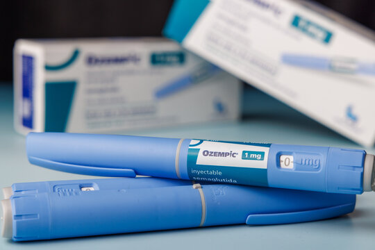 Ozempic 1 mg semaglutide GLP-1 medication pens and boxes on a blue gradient background for pharmaceutical ads about obesity and fitness.  In Barcelona - Spain, January 10, 2026.