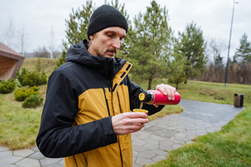 focused beverage transfer, man pours hot drink carefully, individual transferring steaming beverage...