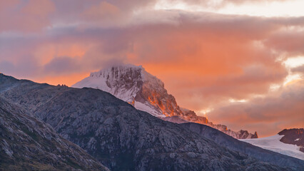 Obraz premium Sunset Mountain Peak in the Strait of Magellan Close Up. Warm Orange Sky with White Snow and Glacier Mountains