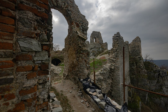 View of weathered stone walls and arches of a crumbling castle against a somber sky, evoking a sense of history and decay, Jelenec, Nitra Region, Slovakia.