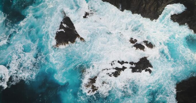 Aerial view of powerful ocean waves crashing against dark volcanic rocks in Tenerife