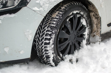 Czarna zimowa opona samochodowa zakopana w śniegu. © Monika