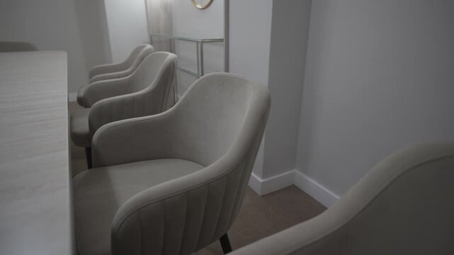 Soft minimalist chairs in milky shade surround long glossy table. Peaceful elegant atmosphere for meetings banquets and negotiations