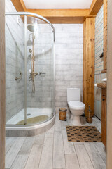 Bright rustic bathroom with glass shower stall and timber beams