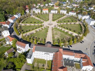 High angle aerial view of Circus Putbus, a unique circular town square with a central obelisk and radiating paths surrounded by white neoclassical buildings. Putbus, Ruegen, Germany