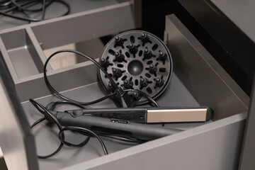 Hair straightener and dryer diffuser neatly organized in a modern gray drawer, essential tools for daily hair care, beauty routine, and efficient storage