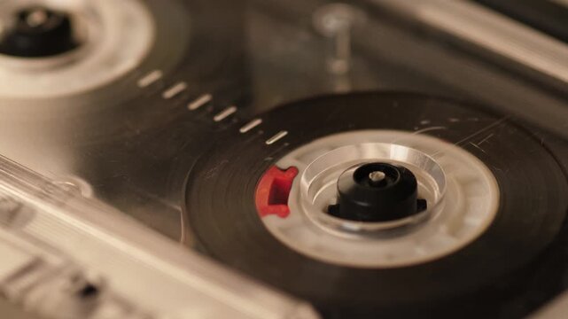 Macro close-up of vintage audio cassette tape spinning in audio player, shallow depth of field