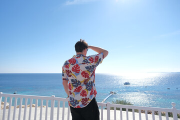 Obraz premium young man in Hawaiian shirt standing on terrace overlooking red sea, Egypt
