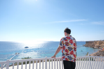 Obraz premium young man in Hawaiian shirt standing on terrace overlooking red sea, Egypt