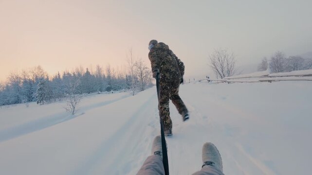 In winter, a guy runs and rides his girlfriend on a sleigh along a trampled path in the forest. Winter outdoor activities. Snow tubbing.  From the first person.
