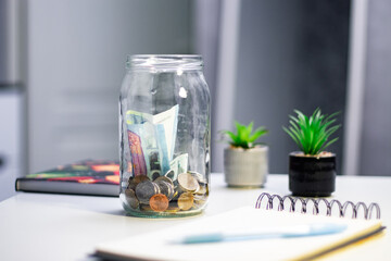 Future planning with long term savings jar. Hand adding substantial savings to future security container. Financial planning and safety concepts